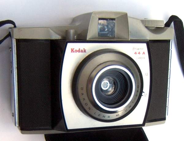 Brownie 44A (Kodak)
APP0552a
-
Nom: Brownie 44A
Marque: KODAK; fabricant: ?; publicité: -
Pays: Grande-Bretagne
Date: début: -1959; fin: -1965
Type: (CFFJ)
Dimensions: 126x87x79mm; poids: ?
Matière: plastique; Couleur: noir/gris
Surface sensible: film 127; format: 4x4cm
Objectif: nom: Dakon; fabricant:?; ouv./focale: ?; fixation : fixe
Diaphragme: type: rotatif; ouvertures: (2 ou 3 ouv.)
Obturateur: nom: central; fabricant: ?; vitesses: 1/40; pose: -
Retardateur: -; Armement: -
Compte-vues: fenêtre (sans cache); Protection 2 expos: -
Synchro flash: oui; flash intégré: -
Posemètre: type: -; plage: -; automatisme: manuel
Mise au point: type: fixe; mini: ?; télémètre: -
Décentrement vert.: -; hor.: -; bascule avant: -; arrière: -
Viseur: galilee; Porte-accessoire: -; Niveau: -
Mode d'emploi: -
Commentaires:
déclencheur gris
Appareil présenté
N° de série: -
N° objectif: -; N° obturateur: -
Accessoires: -; sac: capot
APP0552a.jpg